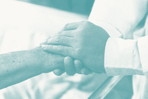 a doctor holds the hand of an older patient